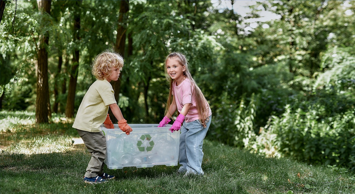 Dzieci na łące z pojemnikiem do recyclingu